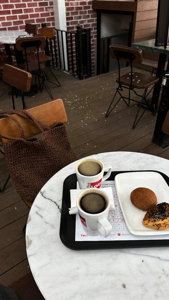 A quaint café scene with coffee and pastries on a marble table, perfect for a relaxing morning.
